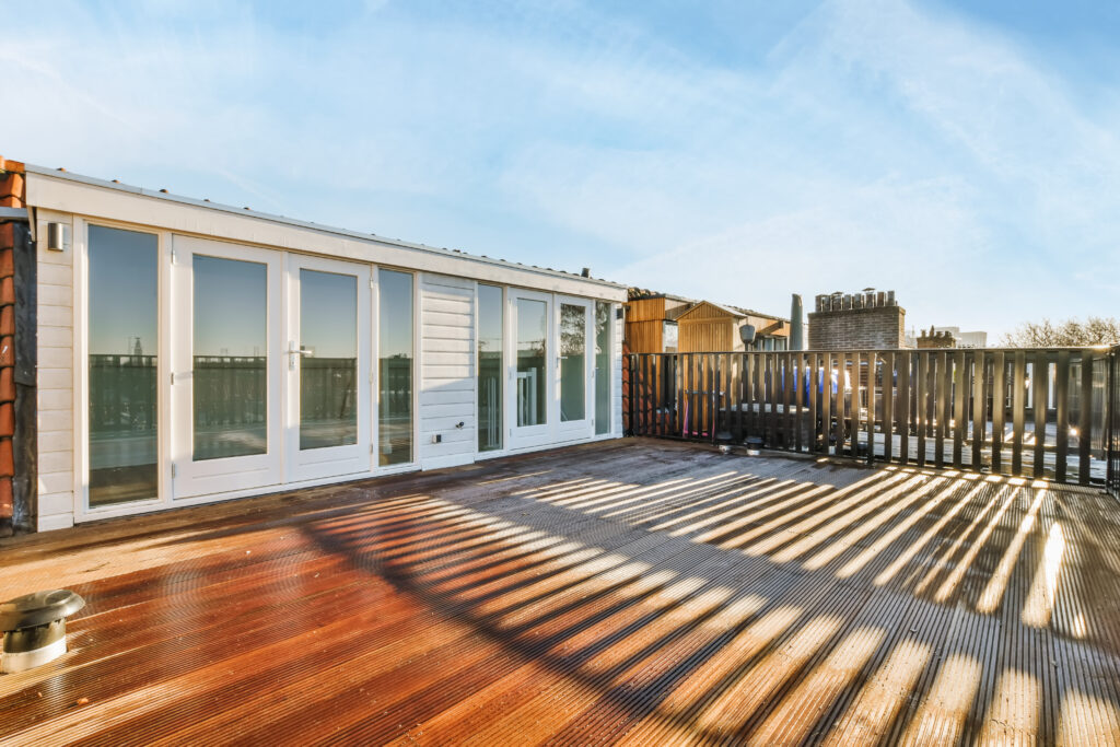 Design of a large balcony with wooden floor and black metal handrails